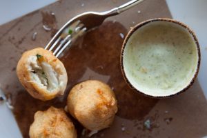 Blue Crab Beignet with dipping sauce in a small bowl with a fork